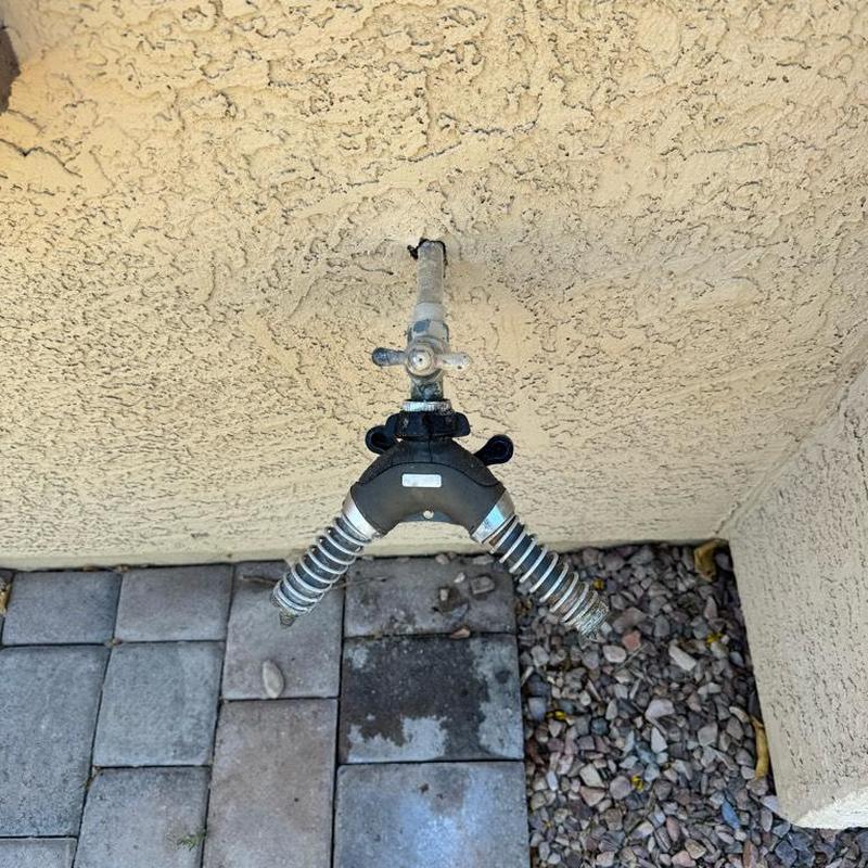Sweat hose bib with hose splitter on stucco wall