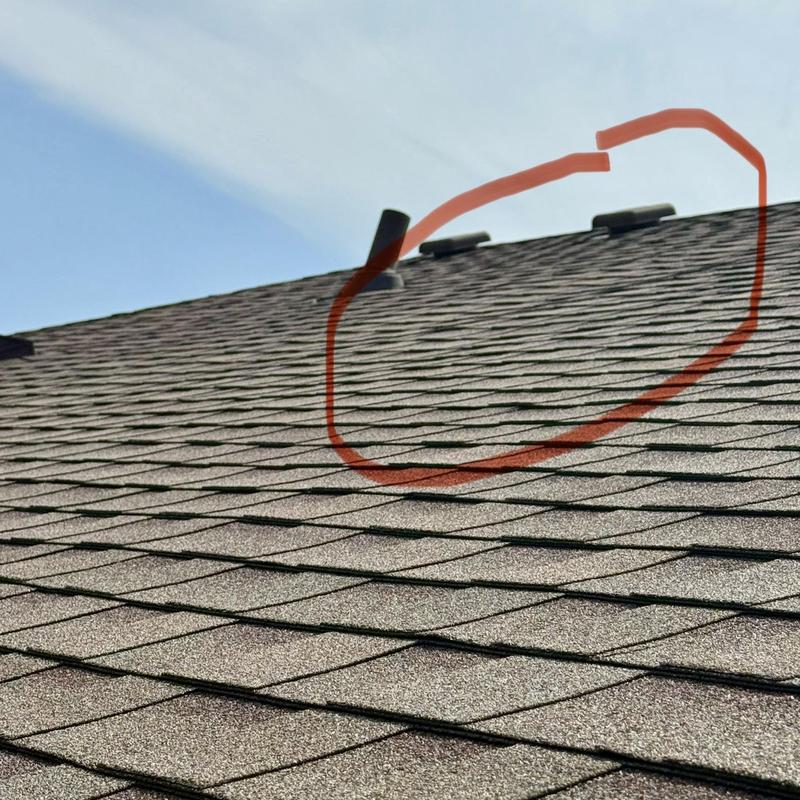 Roof shingles with circled damage on residential roof