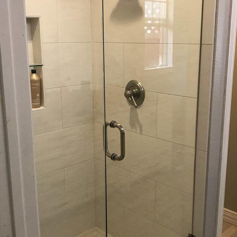 Frameless glass shower enclosure with white tile walls
