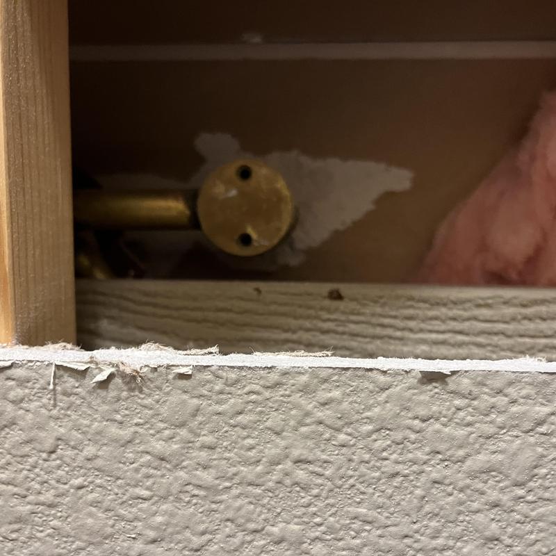 Copper plumbing pipe behind cut drywall for leak inspection