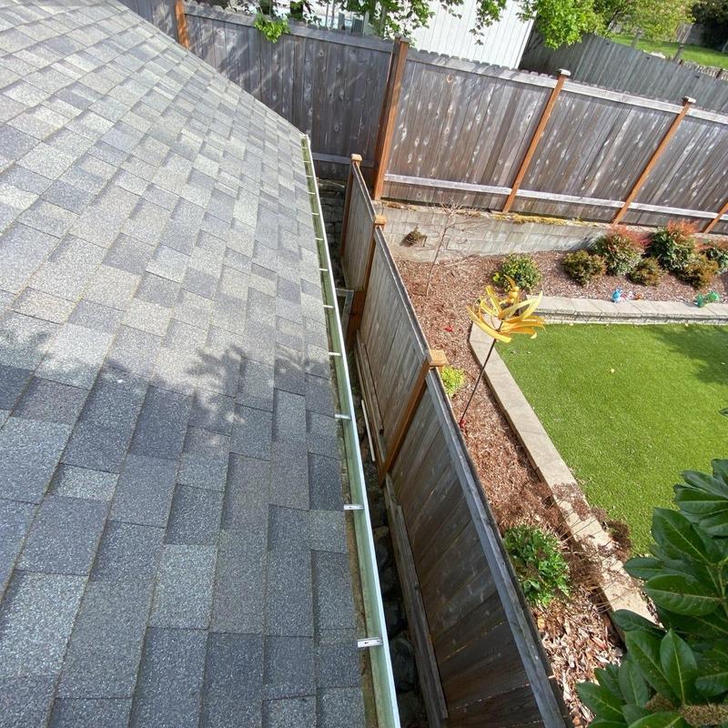 Gutter system with roof shingles and backyard fence