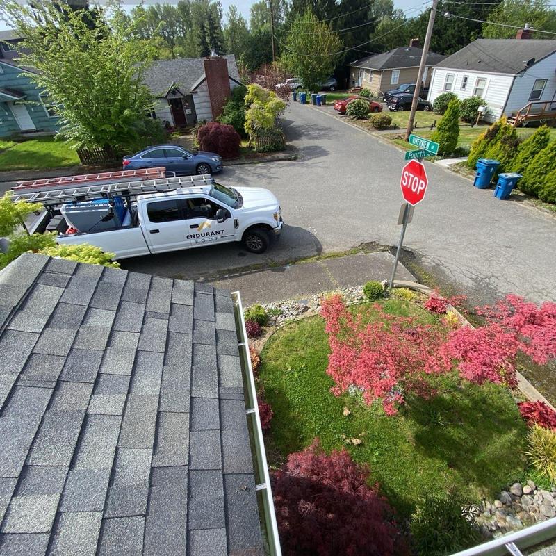 Gutter cleaning on residential roof with Endurant truck nearby