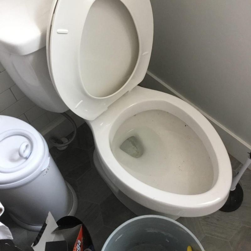 Toilet bowl with open lid and cleaning tools nearby