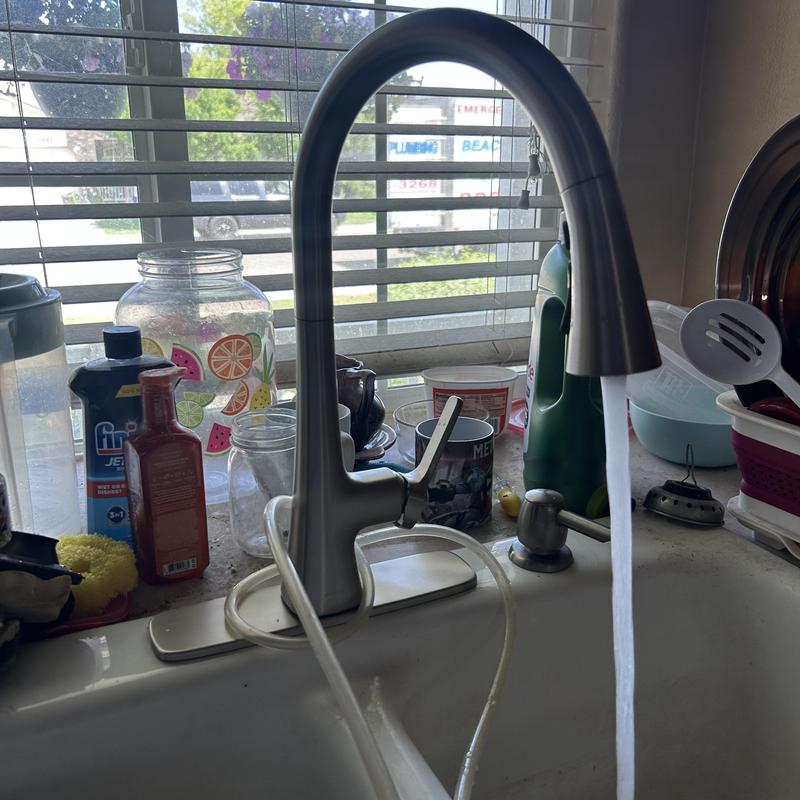 Kitchen faucet with water running and surrounding sink items