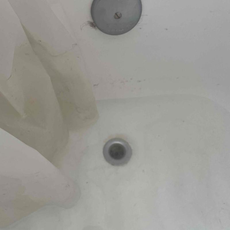 Bathtub drain with curtain showing clogged condition