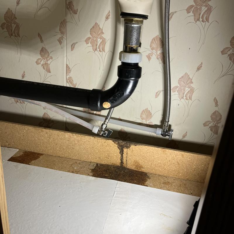 Vanity drain pipe with leak and water damage stains