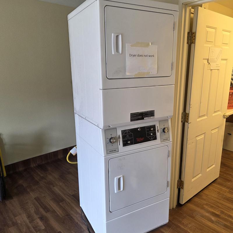 Stacked laundry dryer unit with "does not work" sign