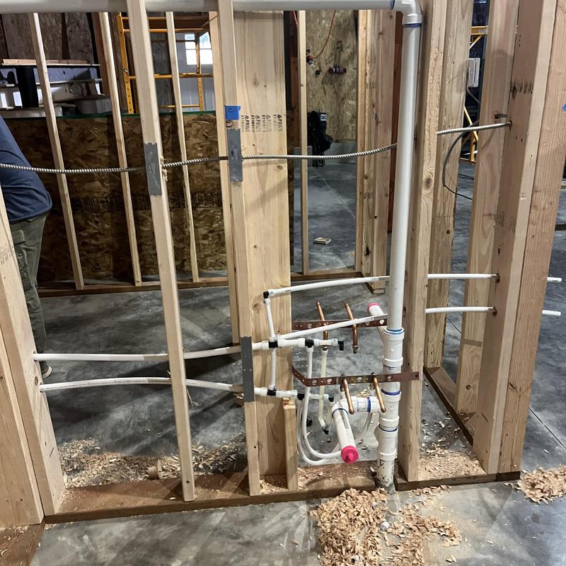 Water and sewer pipes installed in framed wall cavity