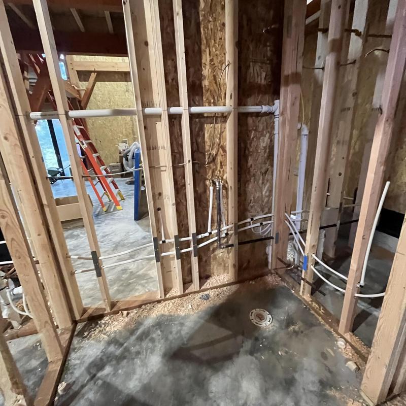 Sewer and water pipes installed in wall framing