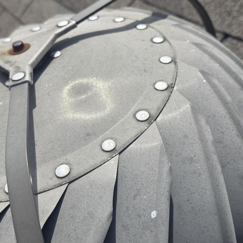 Metal vent cap with wind and hail damage dents