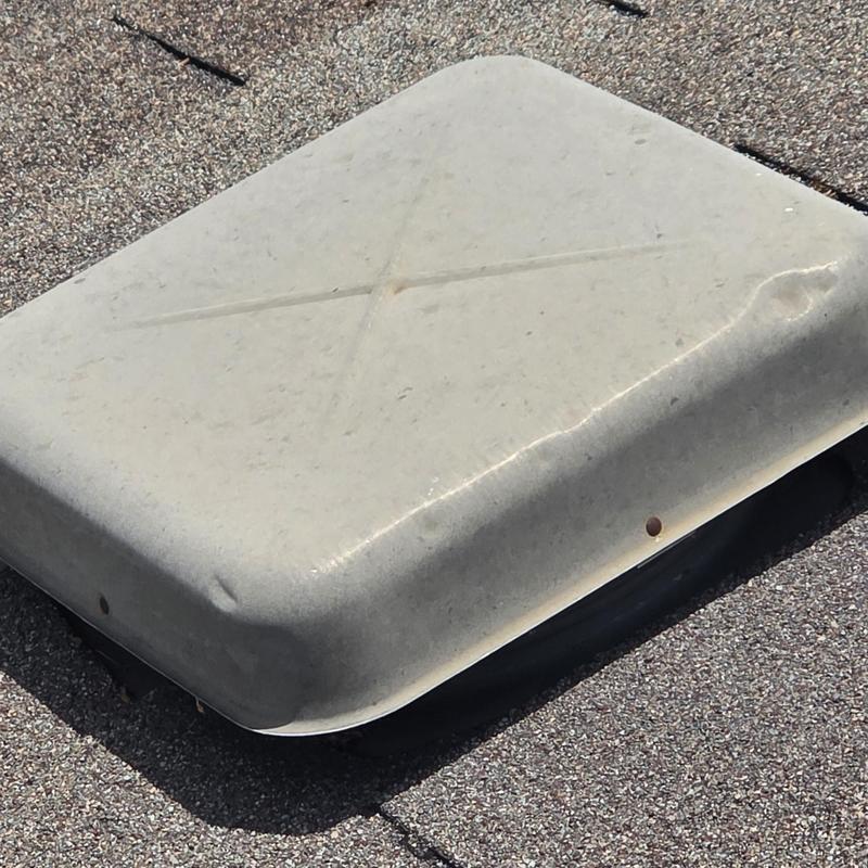 Roof vent cover with hail damage on shingle roof
