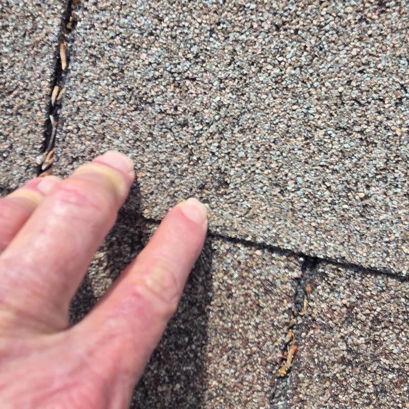 Asphalt roof shingles with wind and hail damage close-up