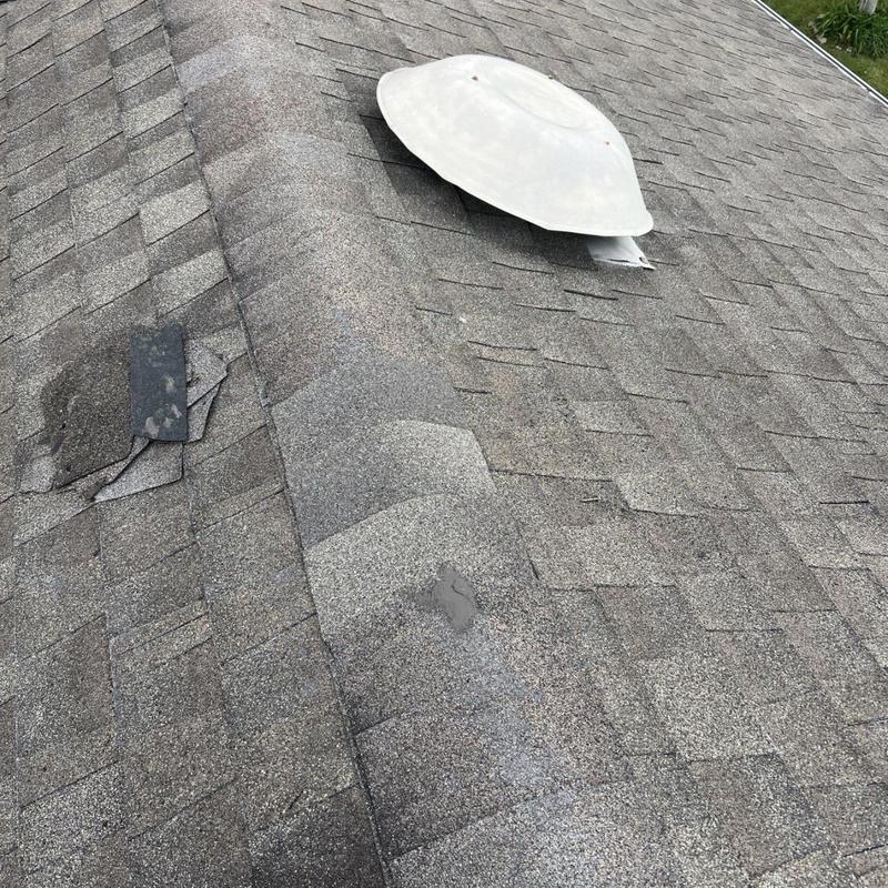 Roof shingles with damaged and missing pieces near vent