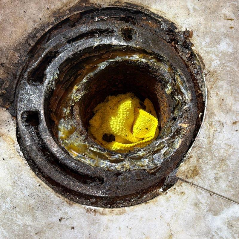 Toilet flange corrosion with yellow cleaning cloth inside