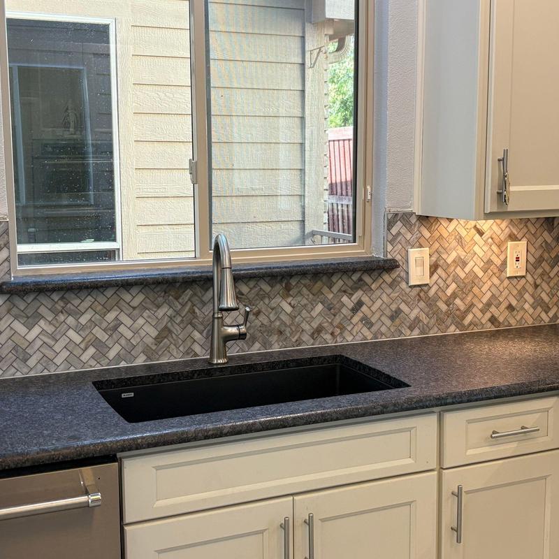 Quartz countertops with leathered finish and herringbone backsplash