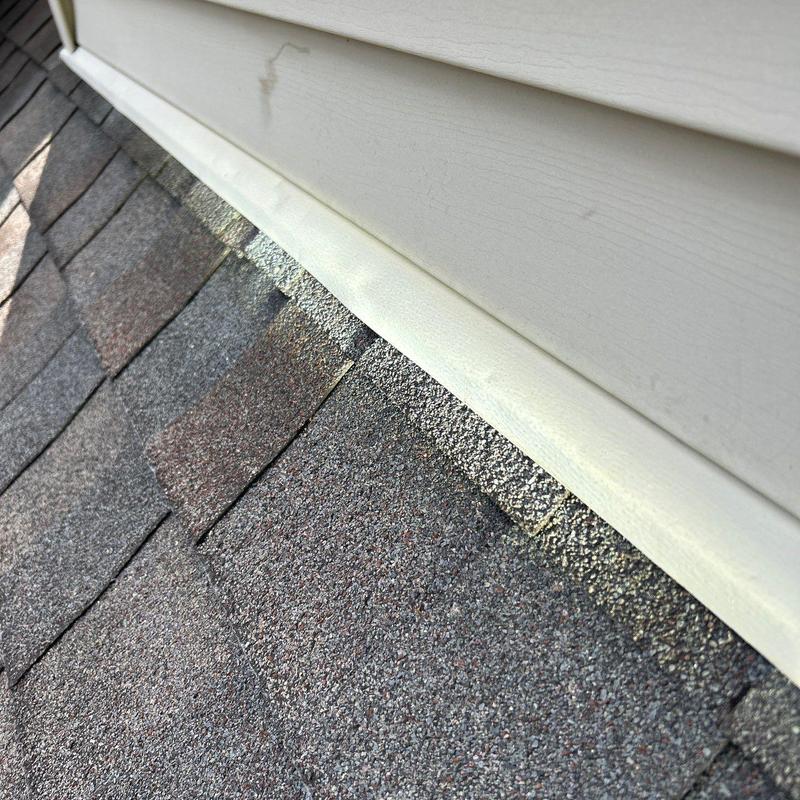 Asphalt shingles roof with hail damage near siding trim