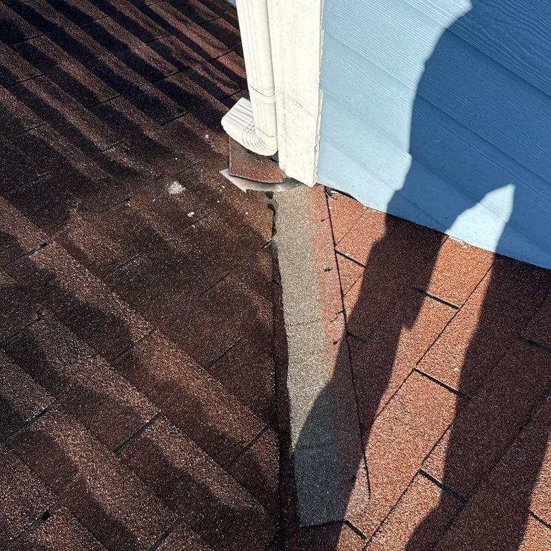 Asphalt roof shingles with hail damage near drainpipe