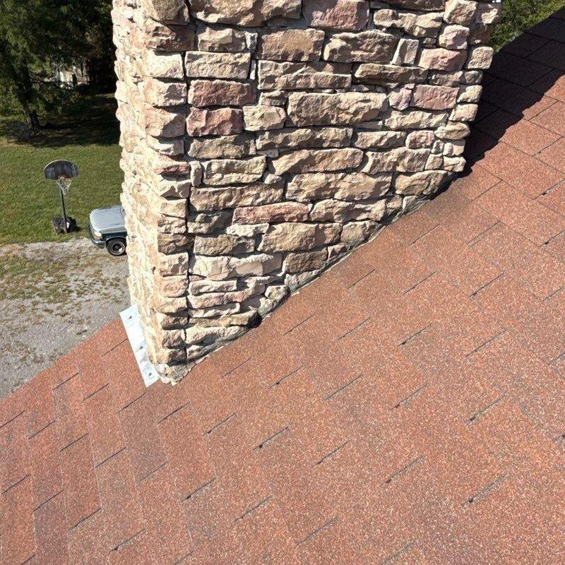 Asphalt shingles around stone chimney roof area