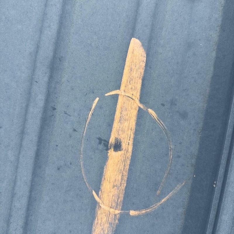 Metal roofing panel hail damage marked for repair