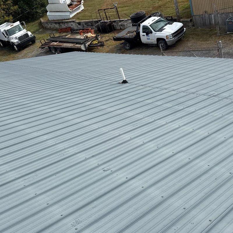 Metal roofing panel with vent pipe and service trucks