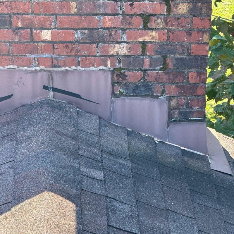 Chimney flashing and shingle roof junction with wear