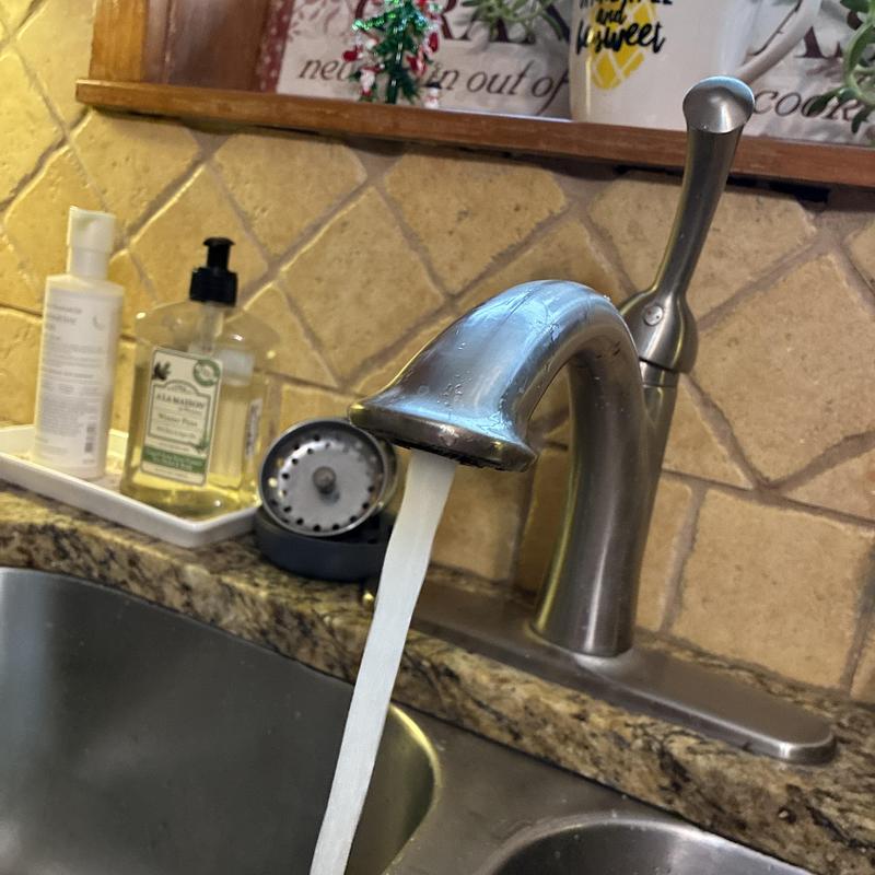 Kitchen faucet with water flowing in granite sink