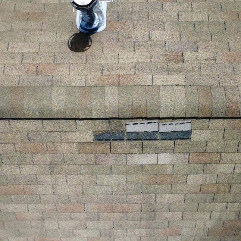 Asphalt shingle roof with damaged shingles and vent pipe
