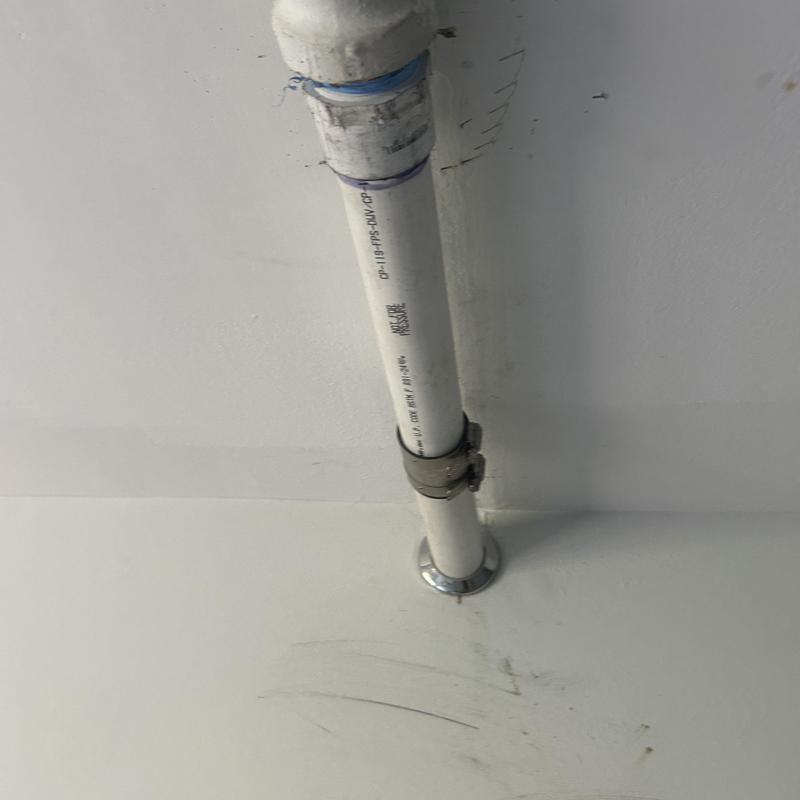PVC plumbing pipe with metal clamp on kitchen ceiling PVC plumbing pipe with metal clamp on kitchen ceiling