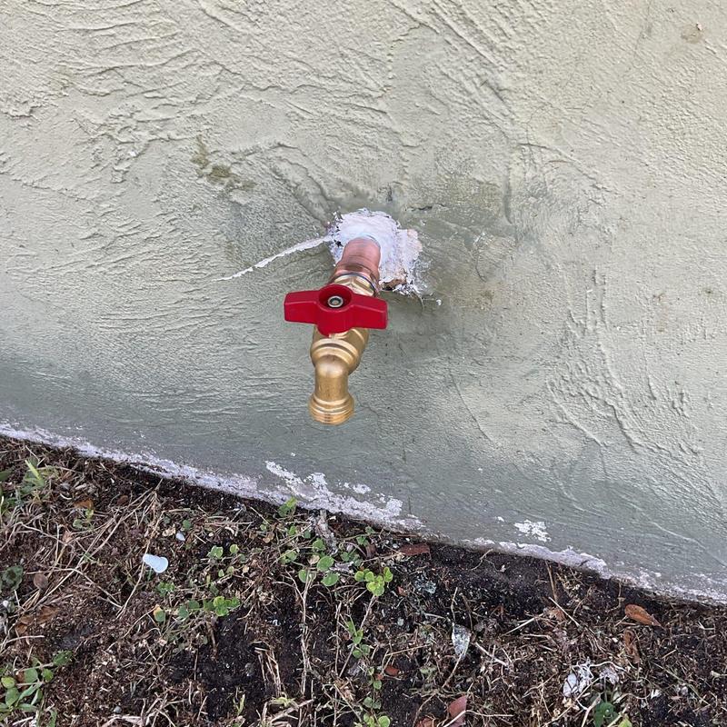 Main valve and hose bibb with red handle on wall