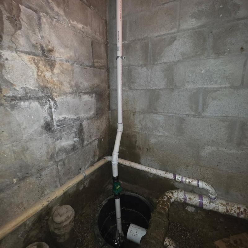 Sump pump system with PVC piping in basement corner