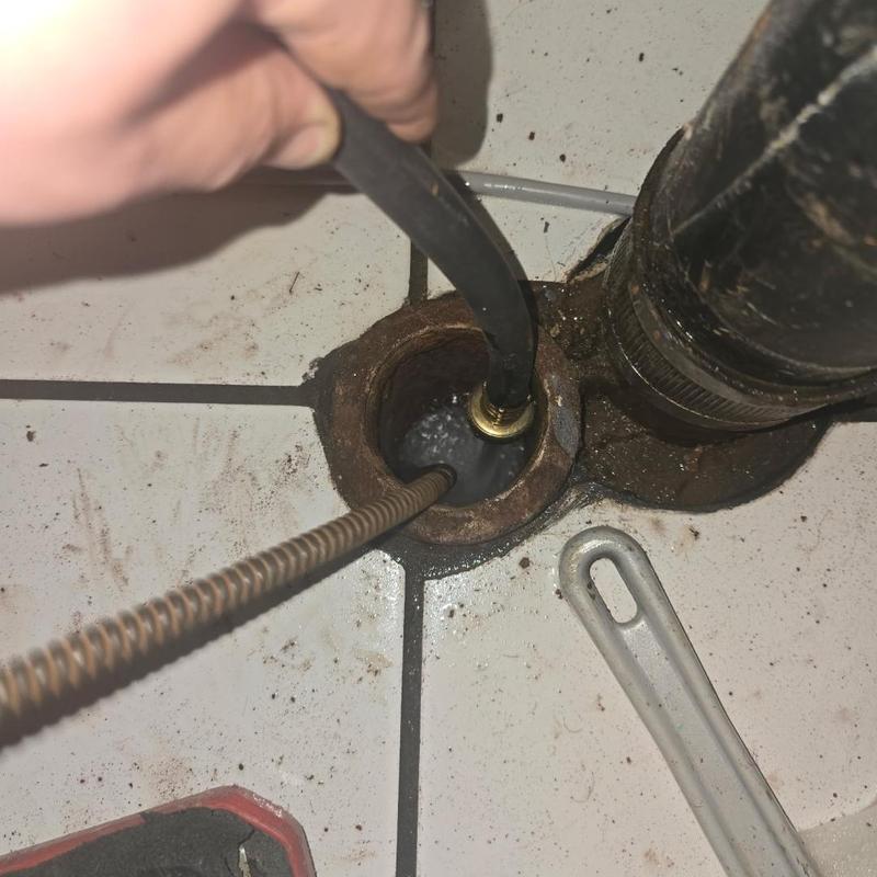 Drain pipe clearing with plumbing snake near stoppage