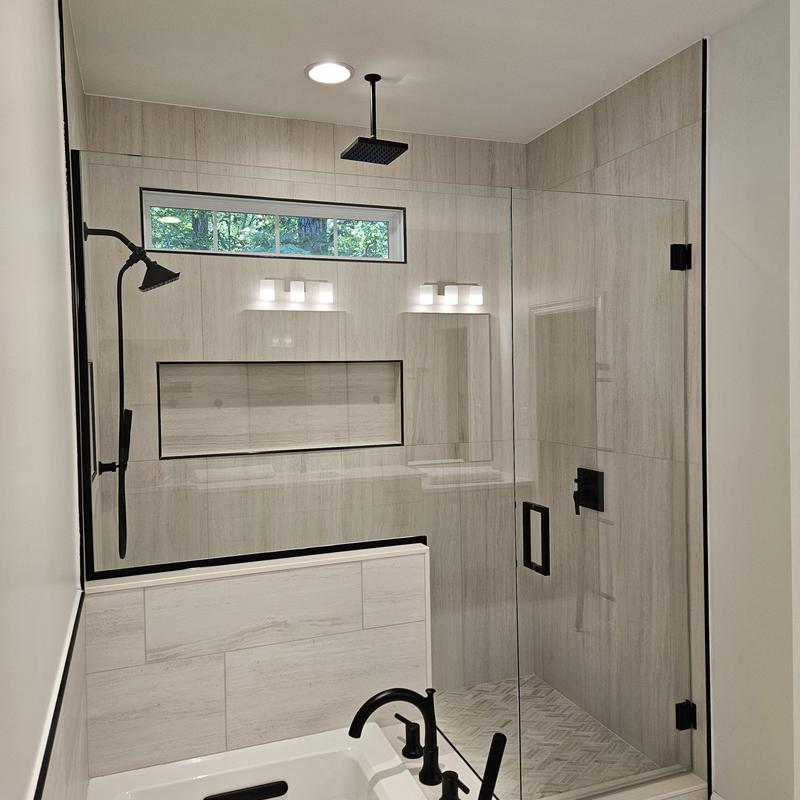 Glass shower enclosure with matte black fixtures in bathroom