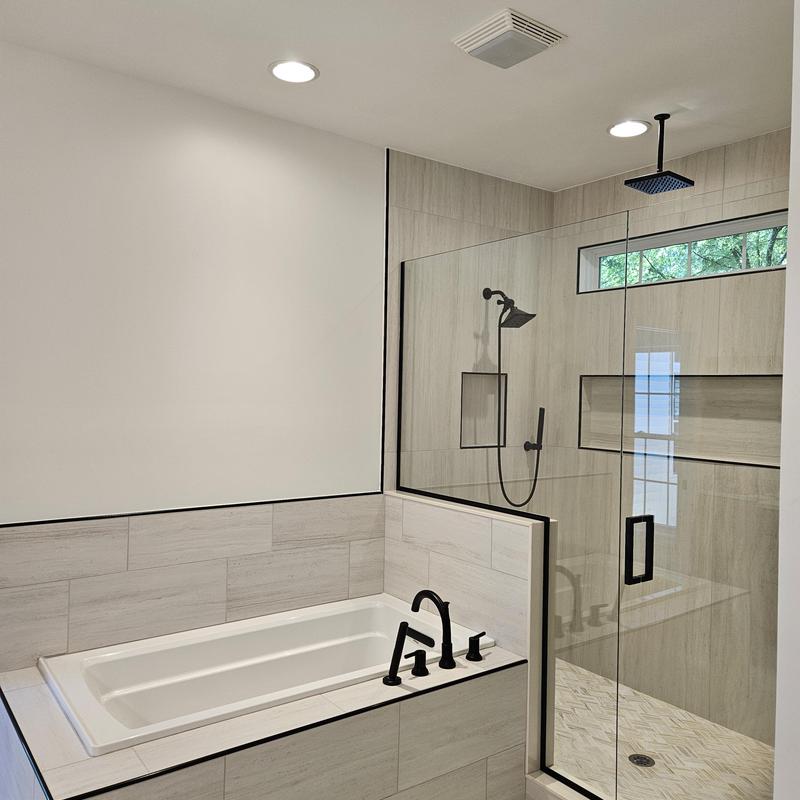 Bathtub and glass shower enclosure with black fixtures