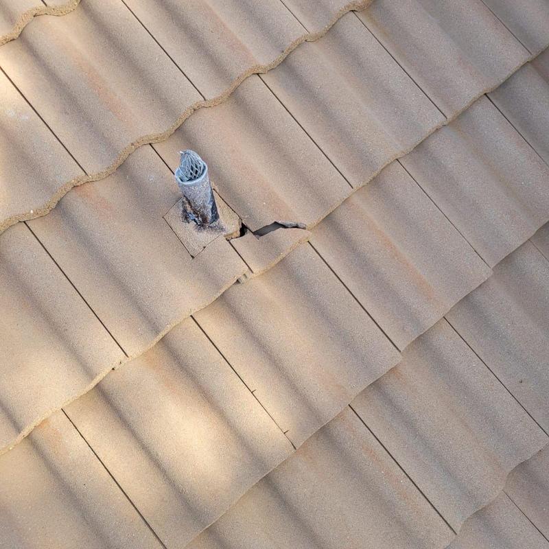 Concrete tile roof with cracked tiles near pipe penetration