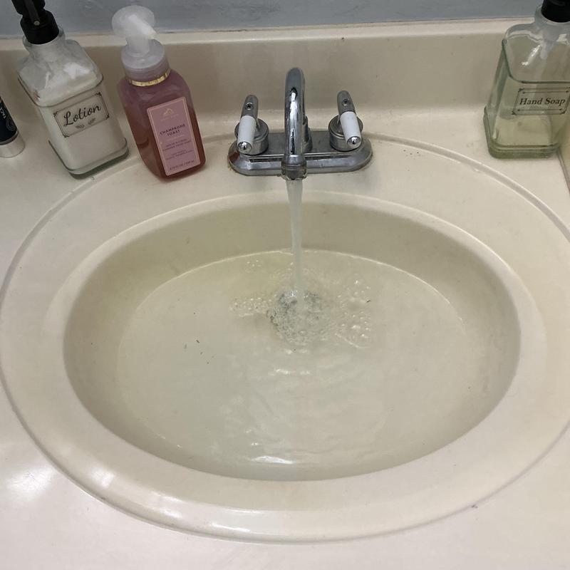 Bathroom sink faucet with running water and soap bottles Bathroom sink faucet with running water and soap bottles