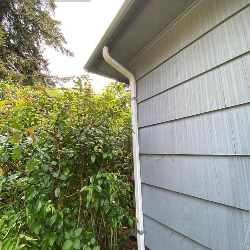 Downspout drainage system on gray exterior wall