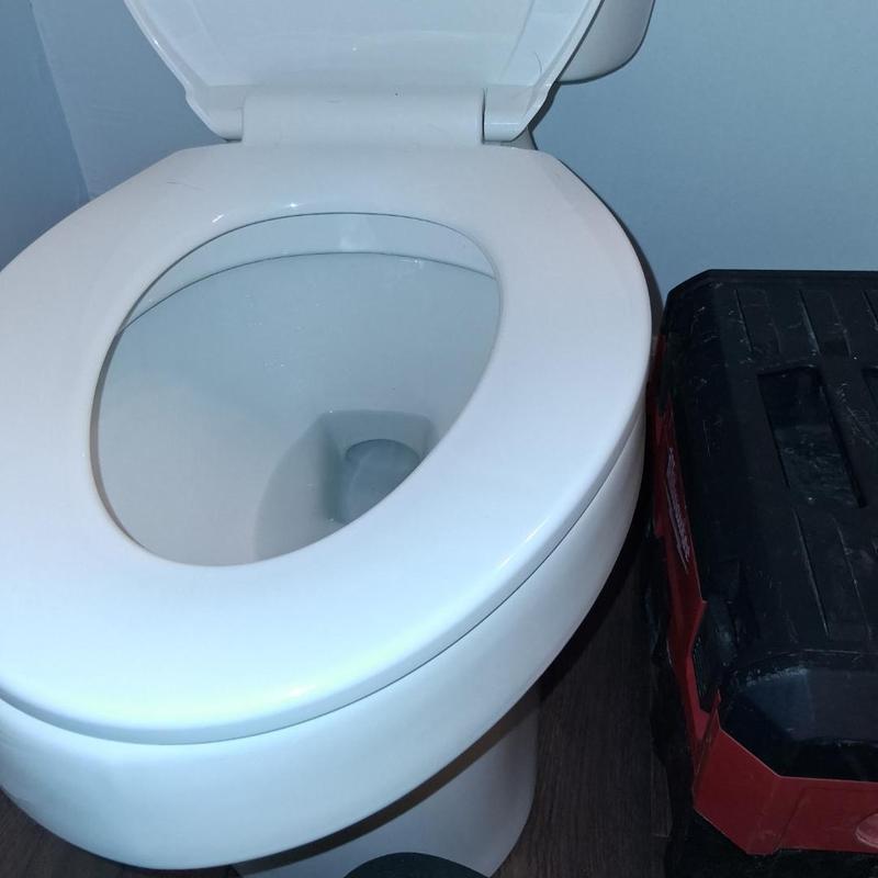 Toilet bowl with open lid and toolbox nearby