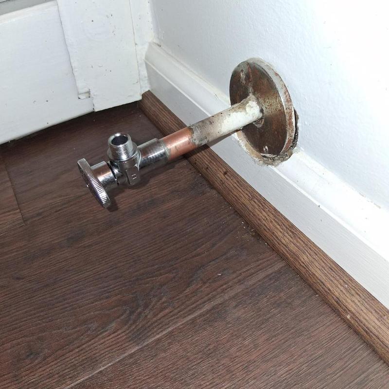 Stop valve with exposed copper pipe in wall corner