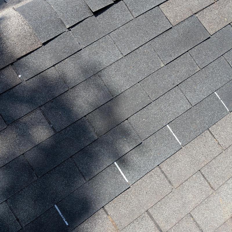 Asphalt shingles with white chalk repair markings on roof