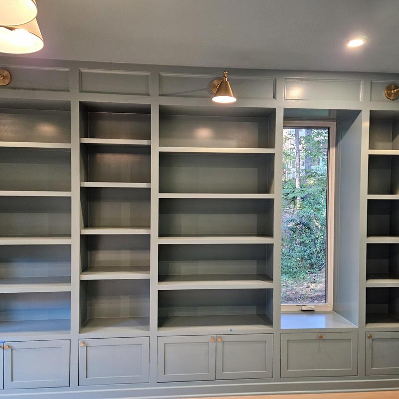 Built-in bookshelf with window nook and brass sconces