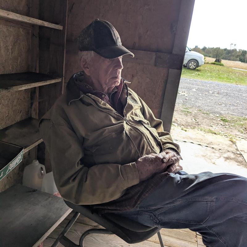 No specific system or item visible; elderly man sitting in shed