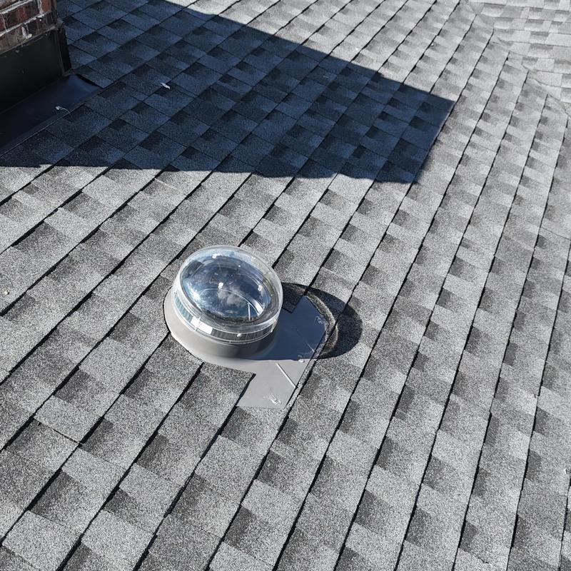 Skylight installation on gray asphalt shingle roof