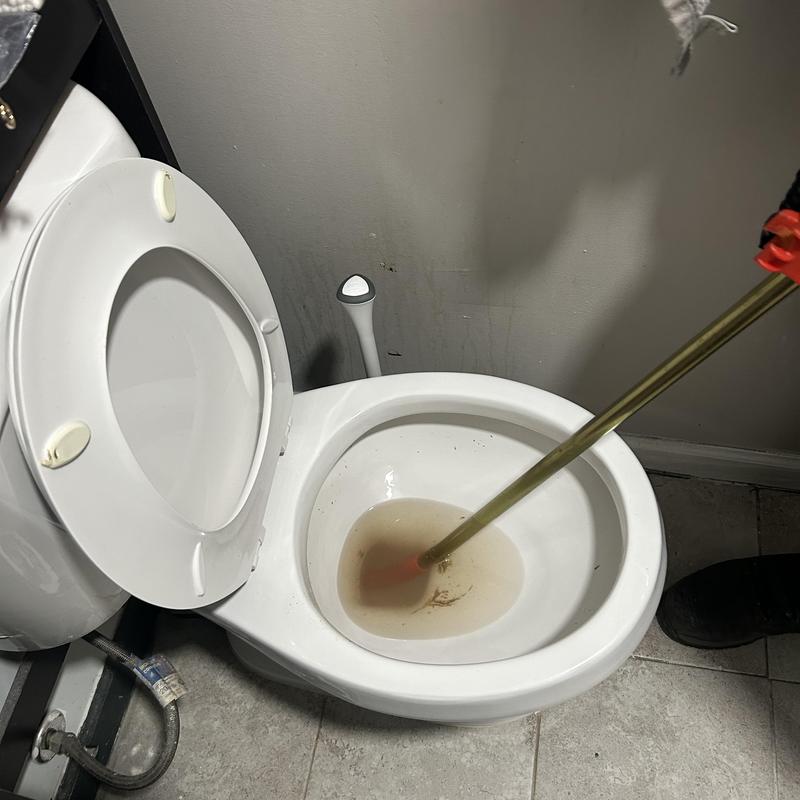 Toilet drain cleaning with plumbing auger in bathroom
