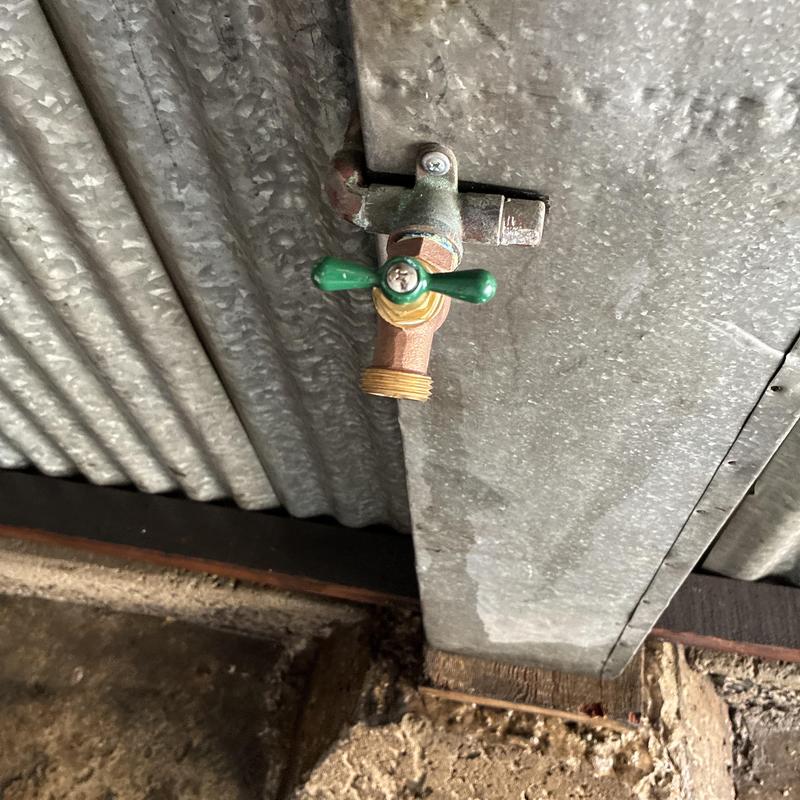 Hose bib valve with green handle on corrugated metal wall Hose bib valve with green handle on corrugated metal wall