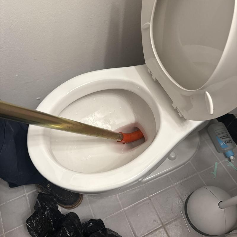 Toilet drain clearing with sewer machine cable in bathroom Toilet drain clearing with sewer machine cable in bathroom