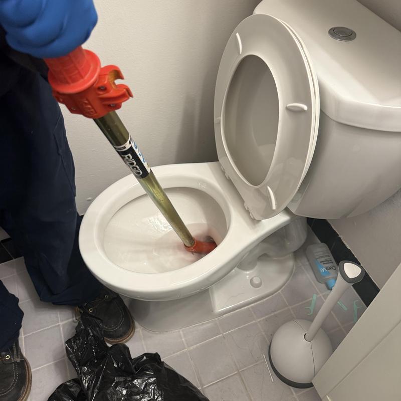 Toilet drain clearing with auger tool in bathroom Toilet drain clearing with auger tool in bathroom
