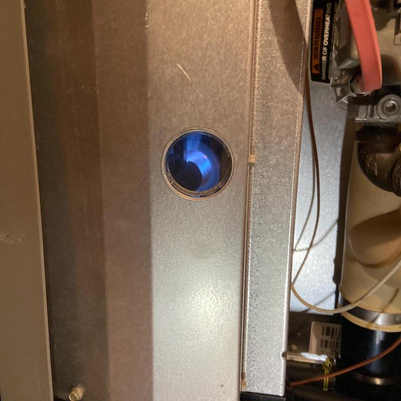 Furnace burner flame visible through inspection window