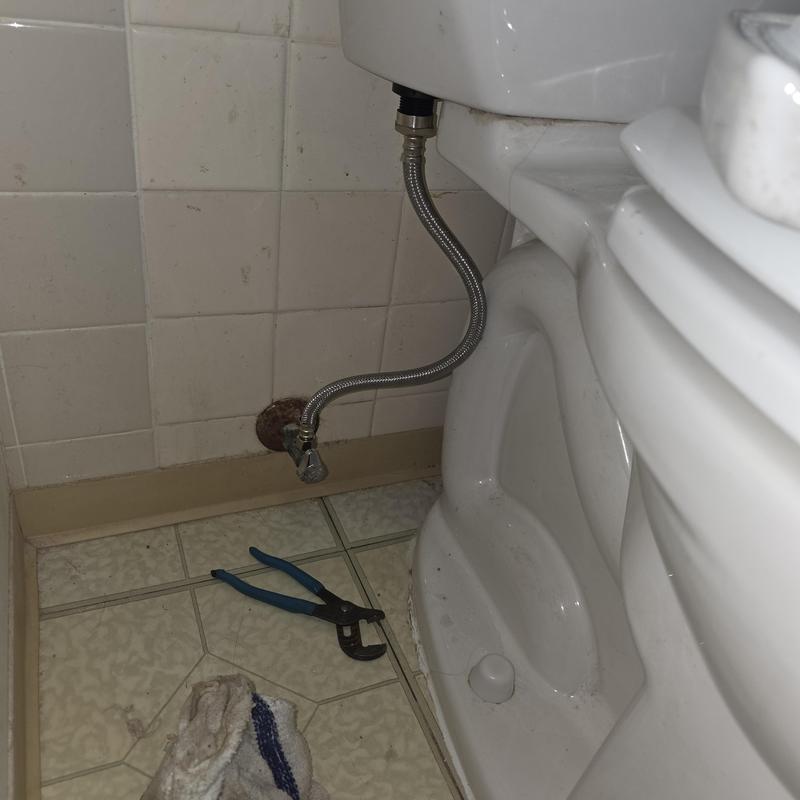 Toilet supply line installation with tools on floor