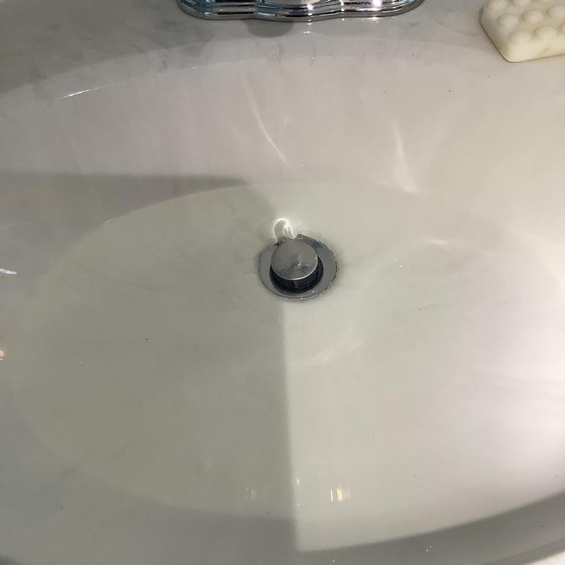 Bathroom sink drain with metal stopper and white countertop Bathroom sink drain with metal stopper and white countertop