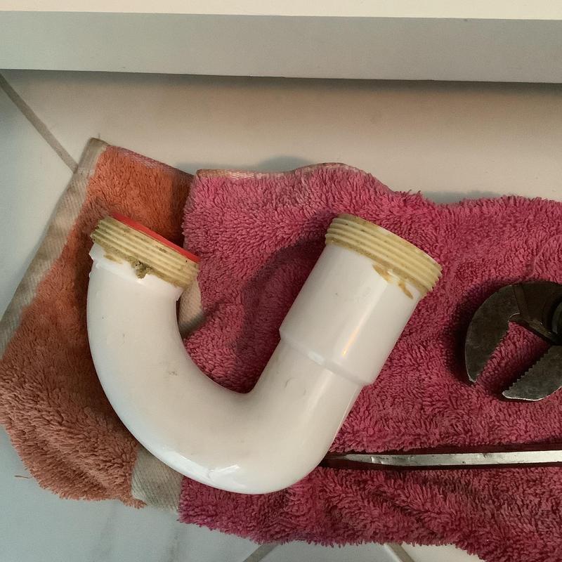 Bathroom sink P-trap pipe and plumbing wrench on towels Bathroom sink P-trap pipe and plumbing wrench on towels